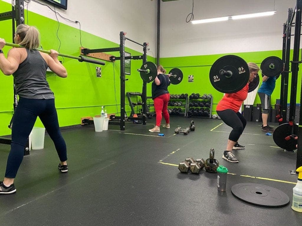 Small Group clients front squatting with barbells