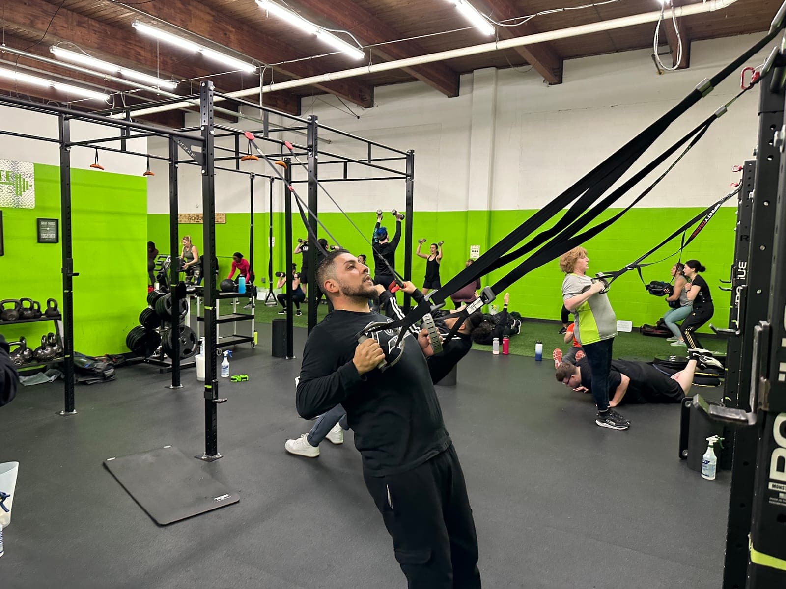 A busy Team Training session, with clients rowing on suspension straps and pressing dumbbells